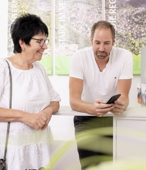 Eine Kundin steht neben einem Berater im Kundencenter